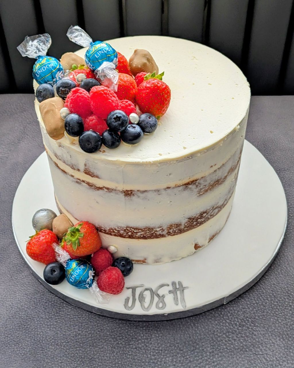 Semi naked cake topped with fresh berries and sweets