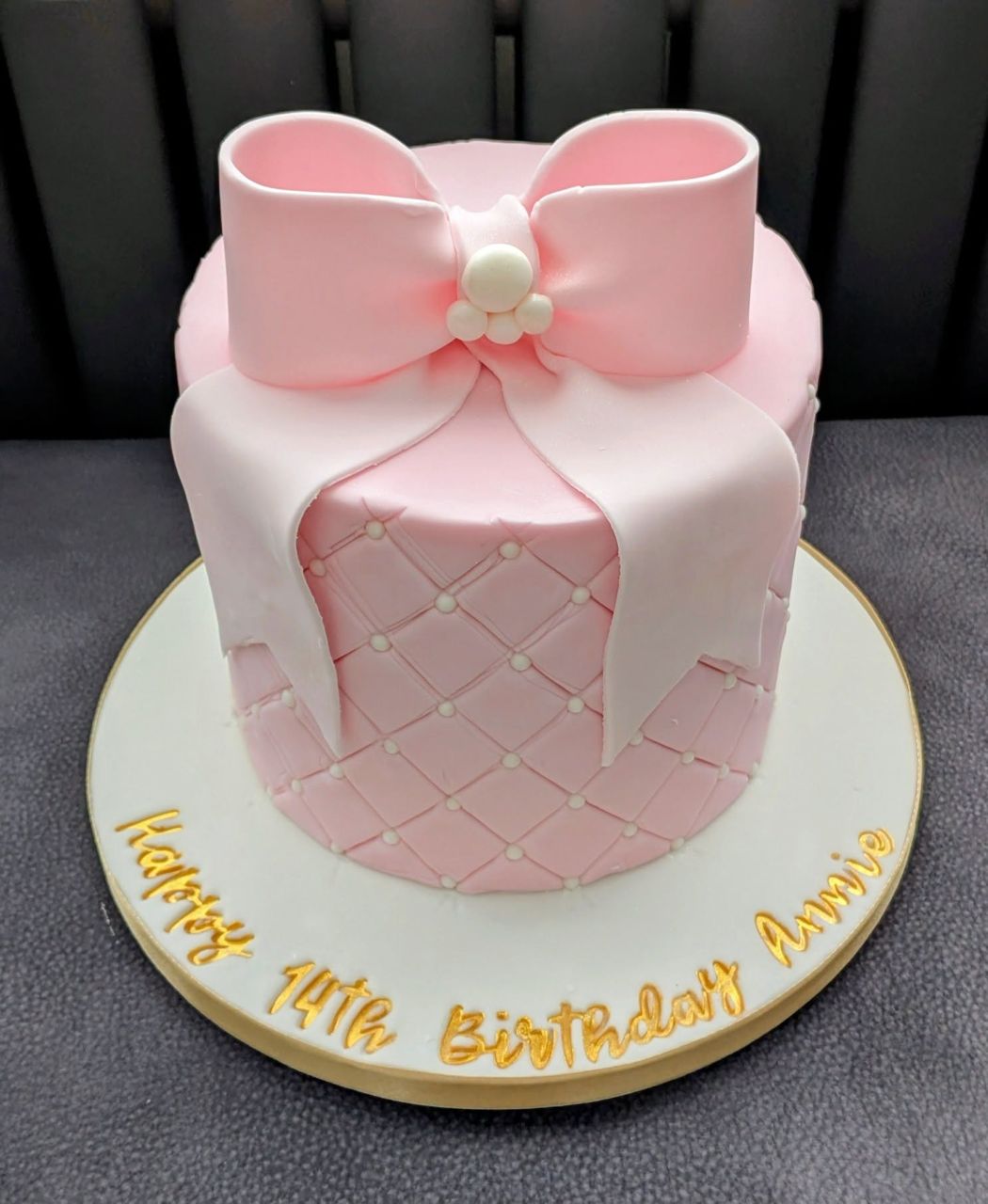 Pink quilted birthday cake with a sugar bow