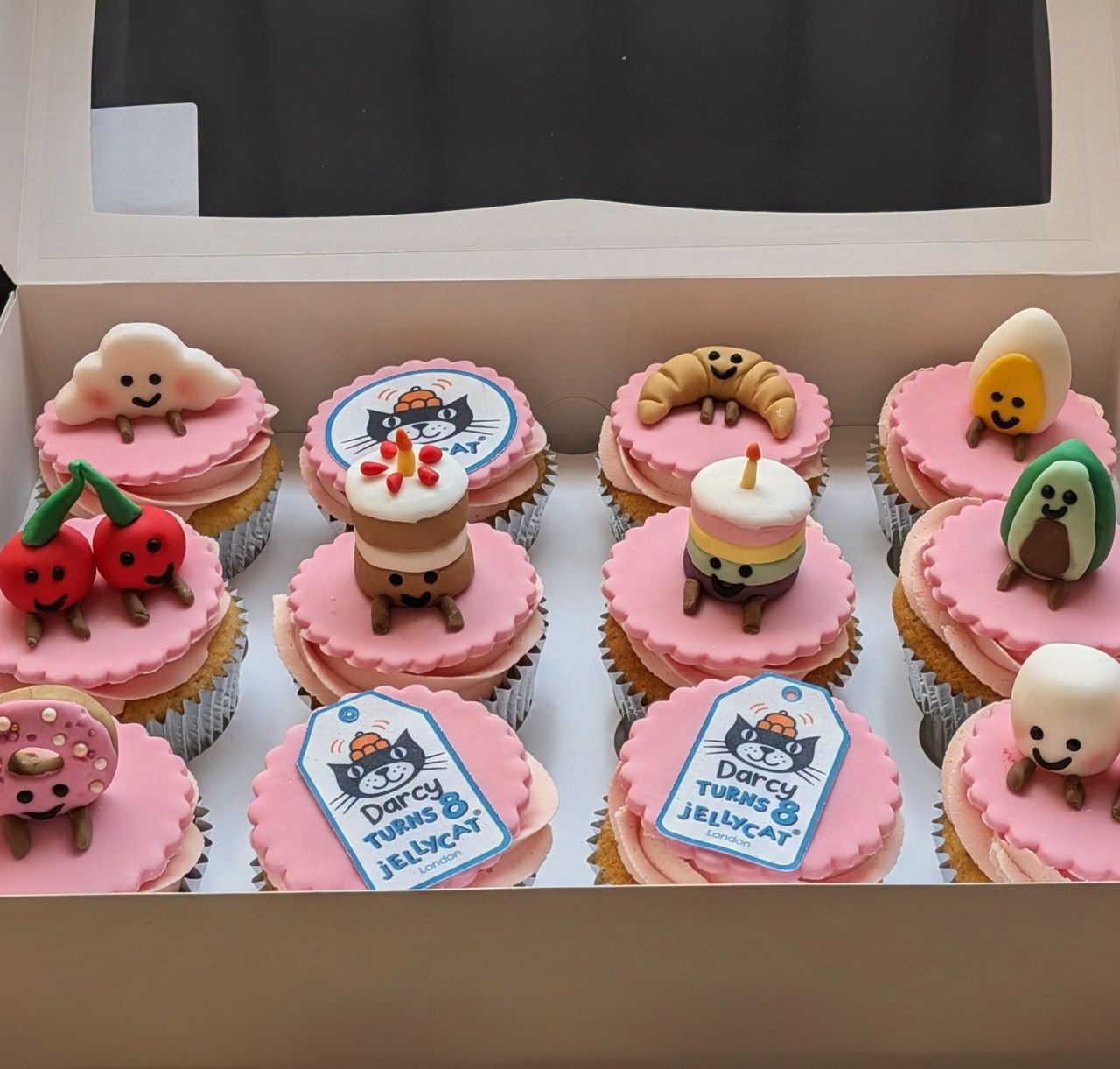 Box of pink themed cupcakes with character toppers